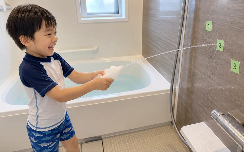 お風呂で水でっぽう遊びで遊ぶ子ども